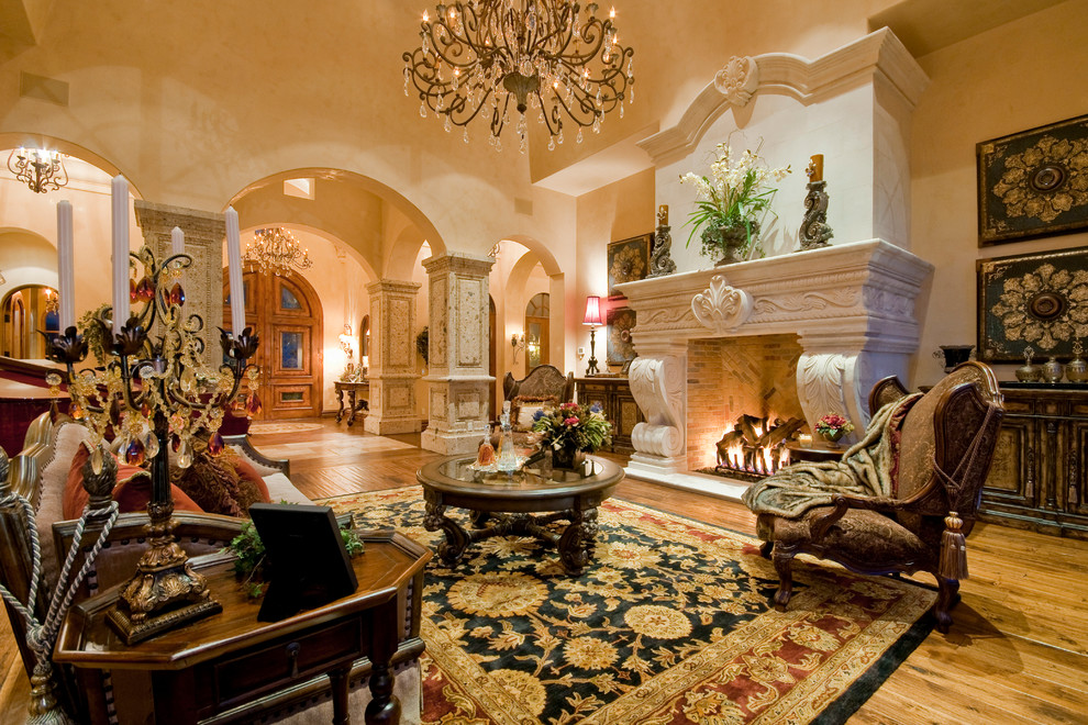 Cette image montre un très grand salon traditionnel ouvert avec une salle de réception, un mur beige, un sol en bois brun, une cheminée standard, un manteau de cheminée en pierre et aucun téléviseur.