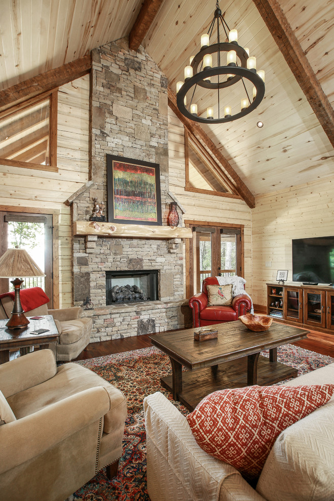 Rustic living room in New Orleans with beige walls, a standard fireplace, a stone fireplace surround, a freestanding tv and feature lighting.