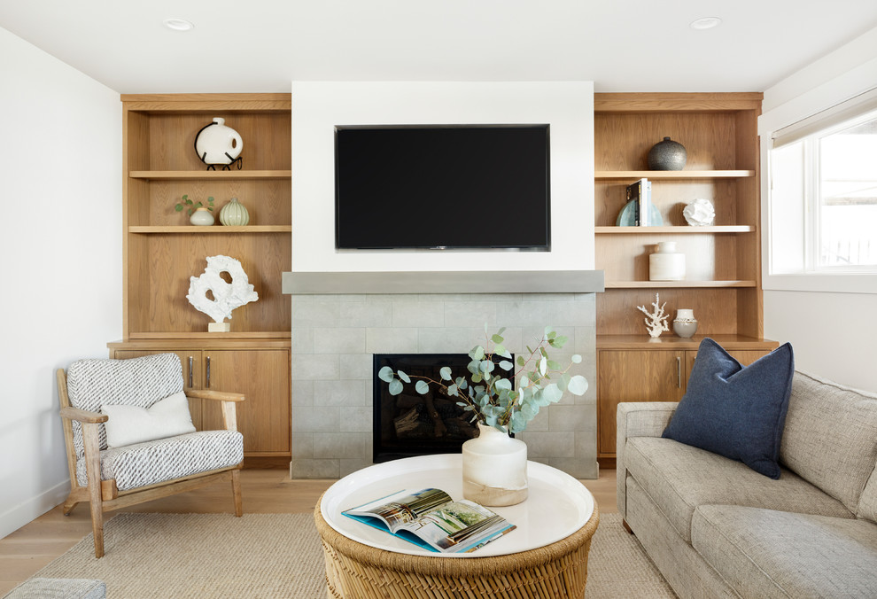 Maritimes Wohnzimmer mit weißer Wandfarbe, hellem Holzboden, Kamin, gefliester Kaminumrandung, TV-Wand und beigem Boden in Seattle
