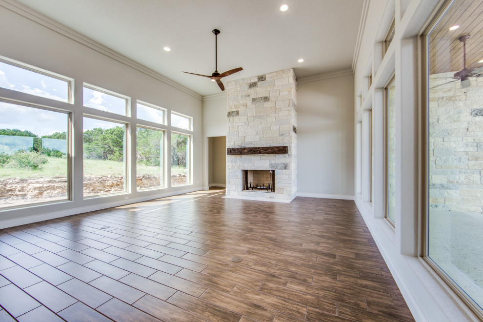 Photo of a large country formal open plan living room in Austin with beige walls, dark hardwood flooring, a standard fireplace, a stone fireplace surround, no tv and brown floors.