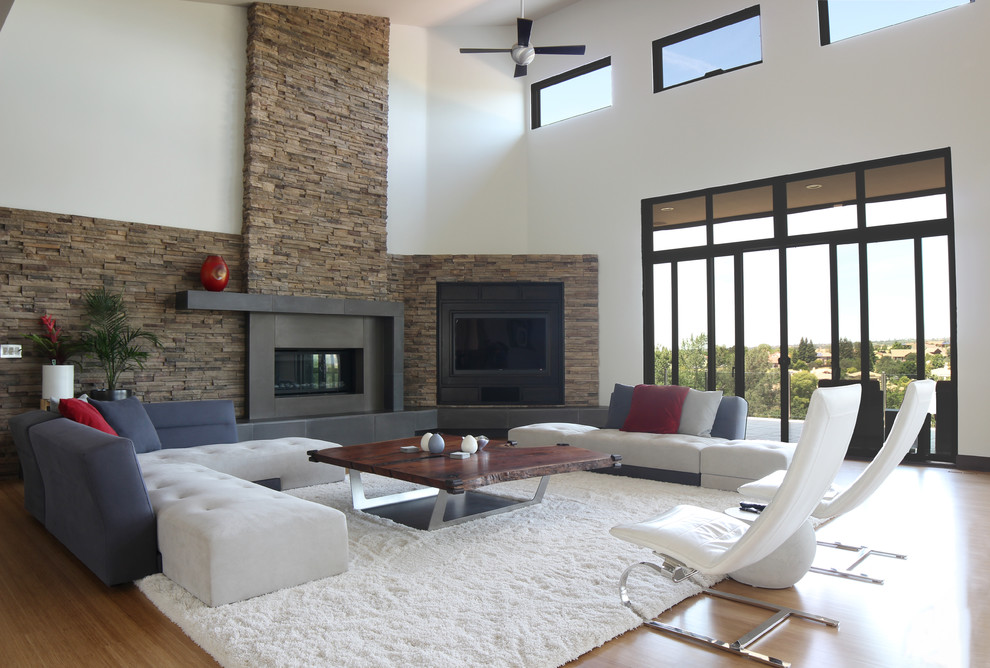 This is an example of a large contemporary formal mezzanine living room in Other with beige walls, bamboo flooring, a standard fireplace, a concrete fireplace surround and a concealed tv.