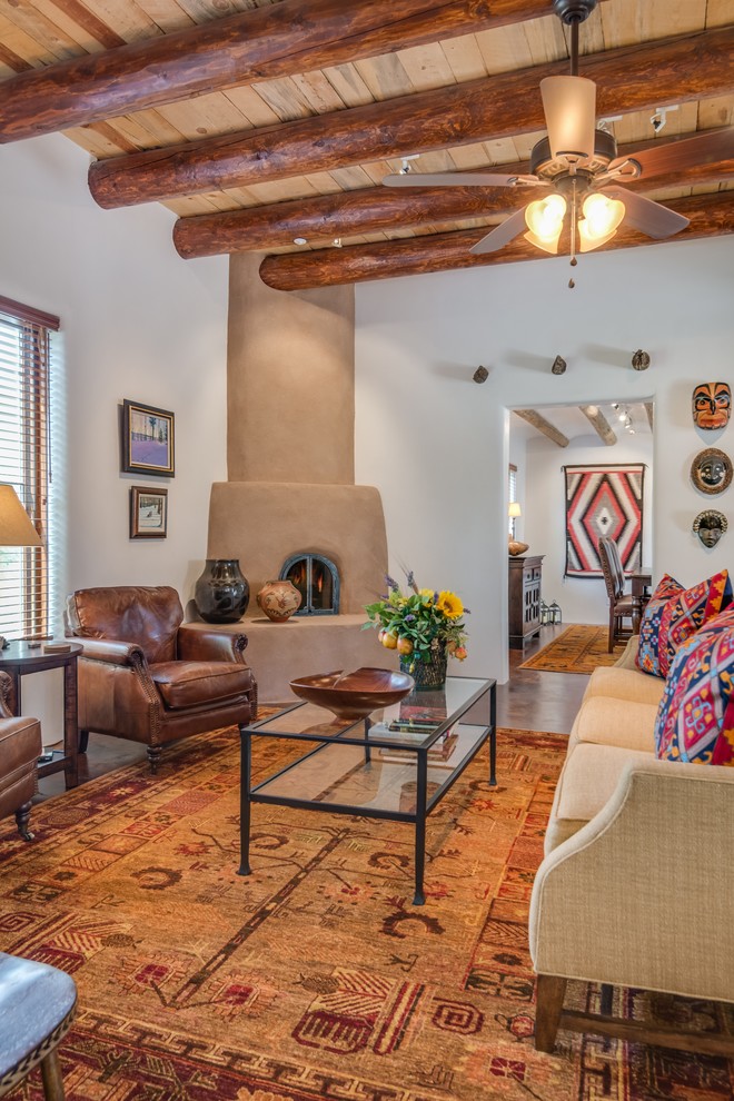 Mittelgroßes, Repräsentatives, Fernseherloses, Abgetrenntes Mediterranes Wohnzimmer mit weißer Wandfarbe, Betonboden, Eckkamin, verputzter Kaminumrandung und braunem Boden in Albuquerque