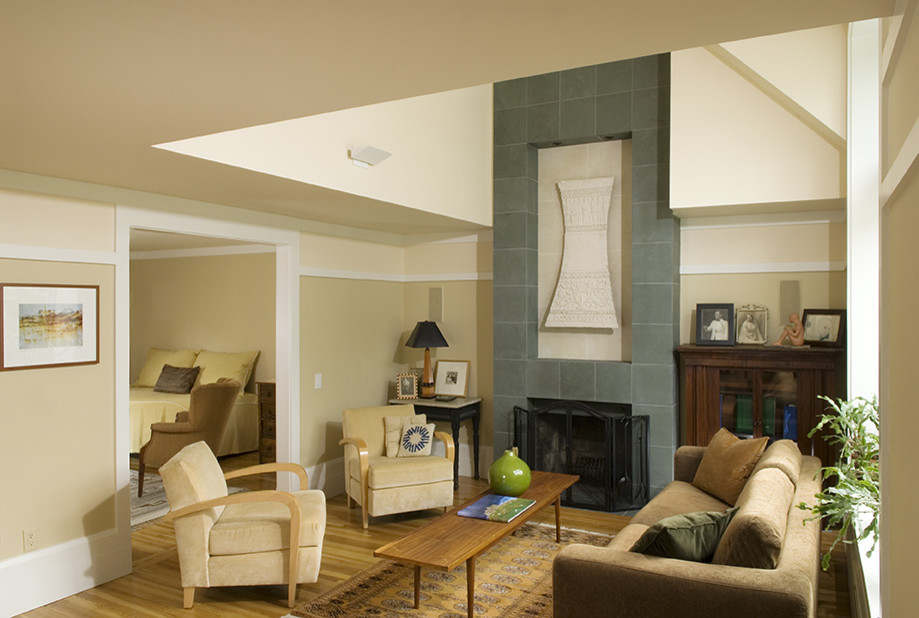 Cette image montre un salon design de taille moyenne et fermé avec un mur beige, un sol en bois brun, une cheminée standard et un manteau de cheminée en pierre.