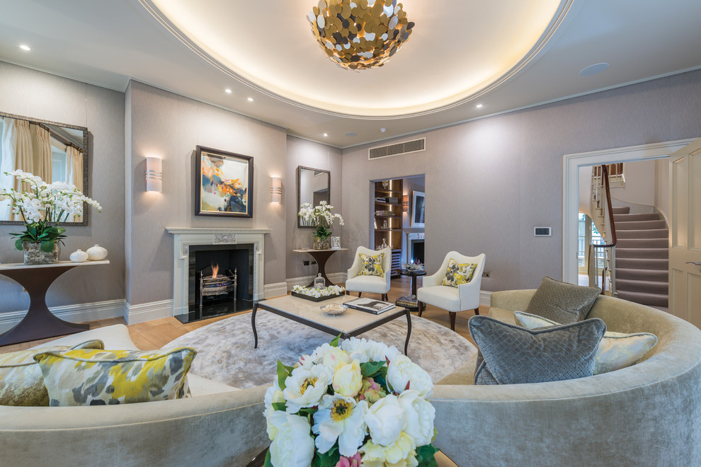 Photo of a traditional formal living room in London with grey walls, light hardwood flooring, a standard fireplace and beige floors.