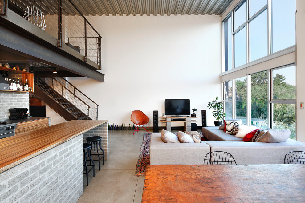 На фото: открытая гостиная комната среднего размера в стиле лофт с бетонным полом, белыми стенами и отдельно стоящим телевизором без камина