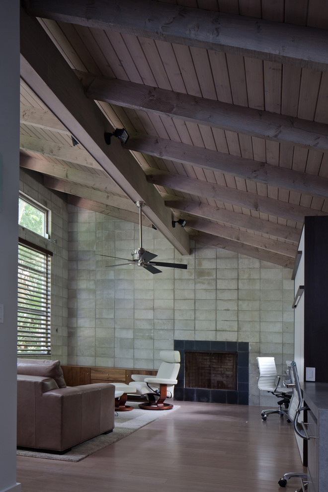 Ejemplo de salón abierto moderno de tamaño medio con paredes grises, suelo de madera en tonos medios, todas las chimeneas y marco de chimenea de piedra