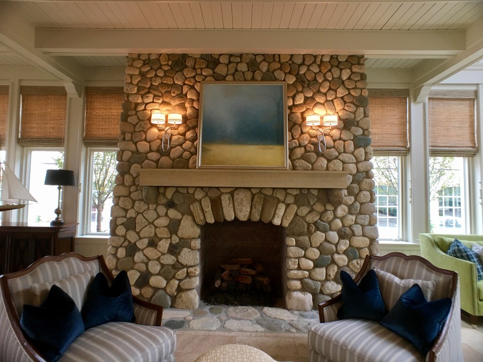 Cette image montre un grand salon traditionnel ouvert avec un sol en calcaire, une cheminée standard, un manteau de cheminée en pierre et un mur blanc.