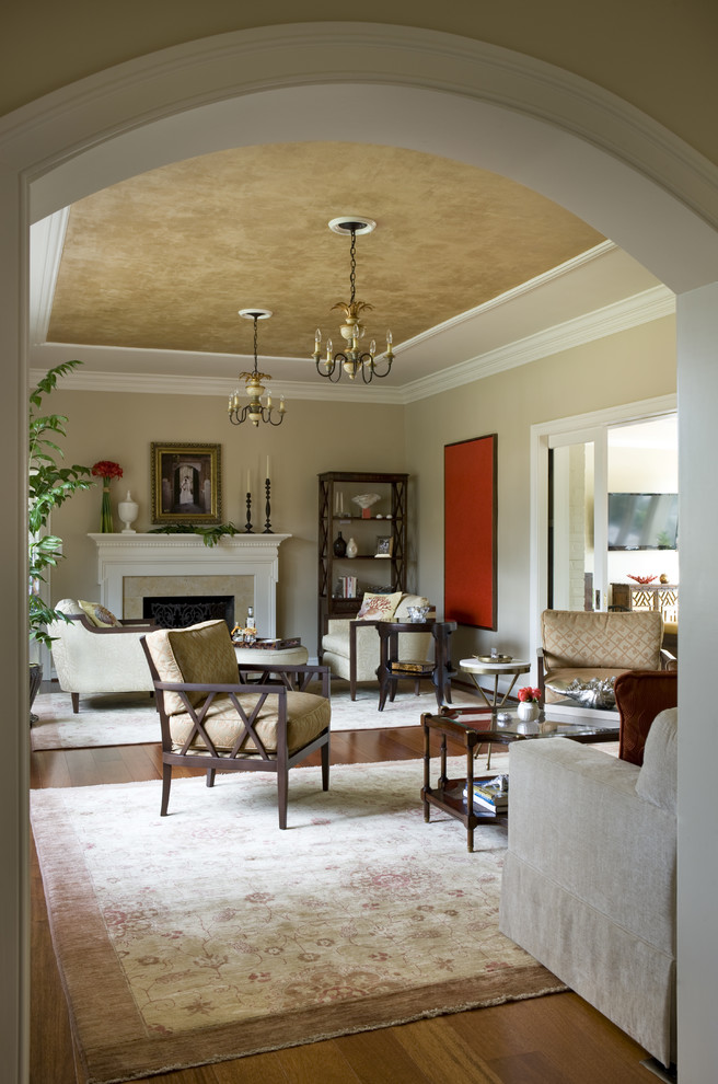 Immagine di un soggiorno classico con pareti beige, pavimento in legno massello medio, camino classico e cornice del camino in pietra