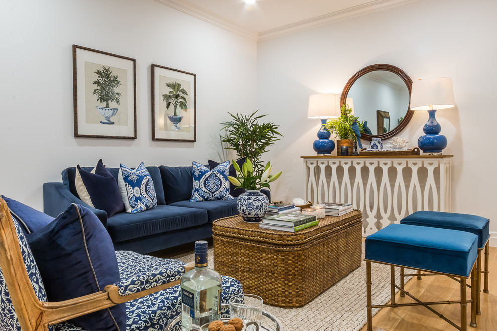 Стильный дизайн: гостиная комната в морском стиле с белыми стенами, светлым паркетным полом и синим диваном - последний тренд