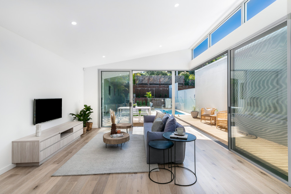Offenes Modernes Wohnzimmer mit weißer Wandfarbe, braunem Holzboden, TV-Wand, braunem Boden und gewölbter Decke in Sydney