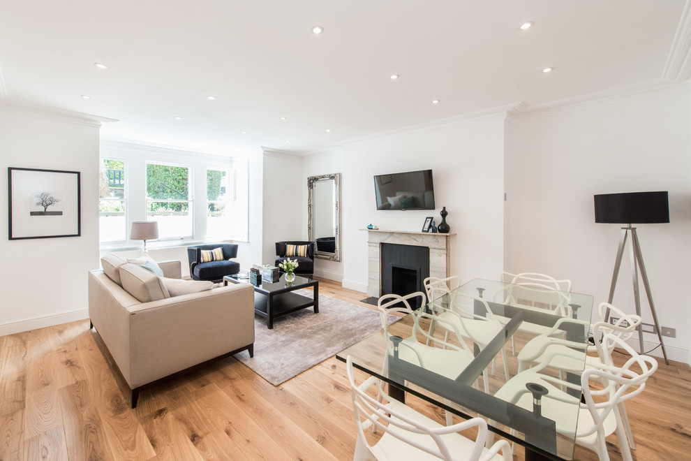 Offenes Modernes Wohnzimmer mit weißer Wandfarbe, braunem Holzboden, Kamin, Kaminumrandung aus Stein, TV-Wand und beigem Boden in London