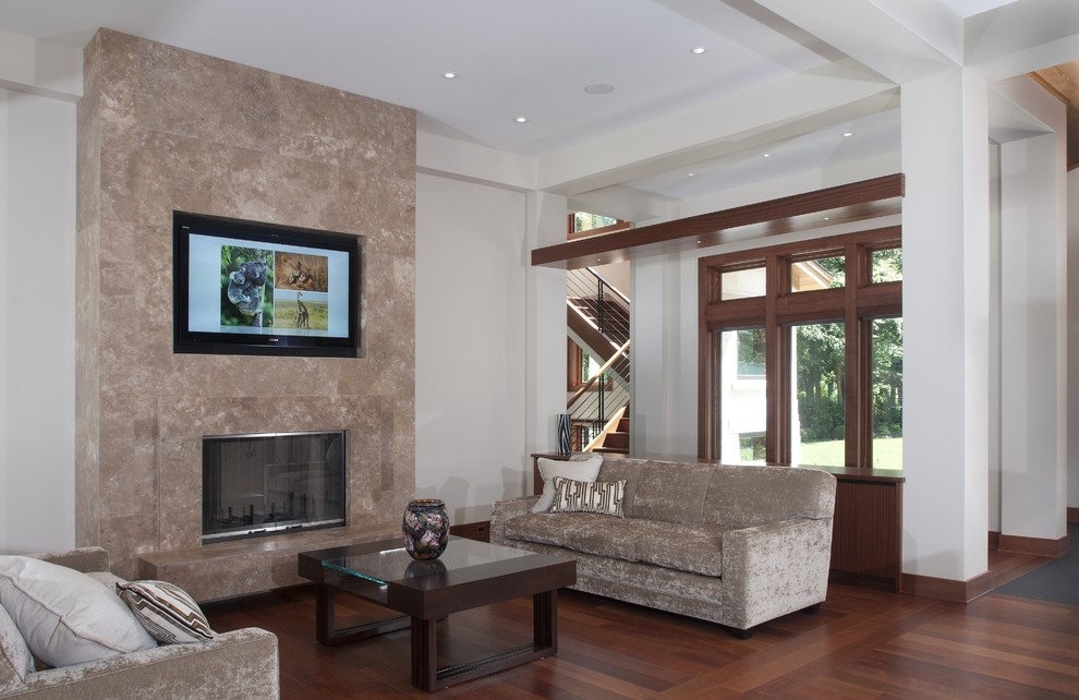 Exemple d'un grand salon tendance ouvert avec un mur blanc, un sol en bois brun, une cheminée standard, un manteau de cheminée en pierre et un téléviseur fixé au mur.