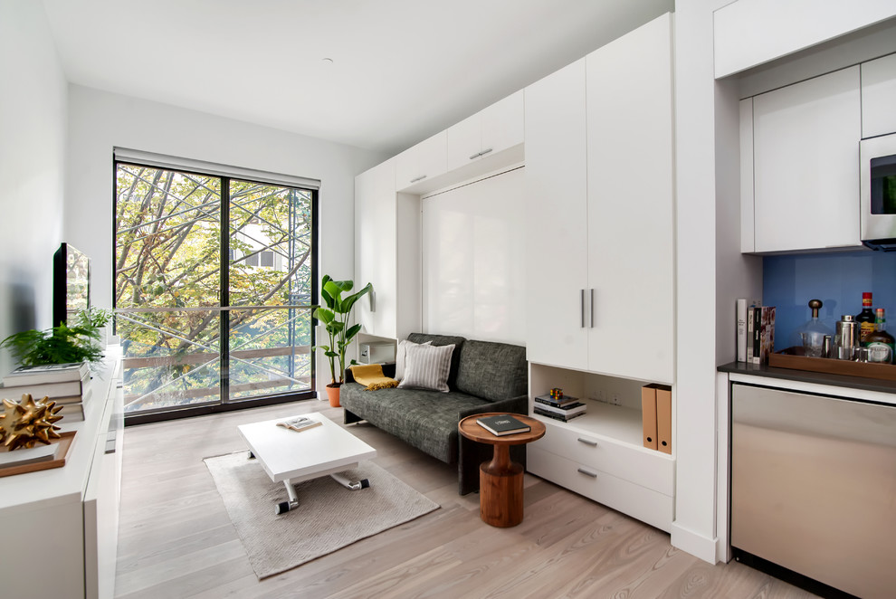 Modern inredning av ett vardagsrum, med ljust trägolv, en fristående TV och vita väggar