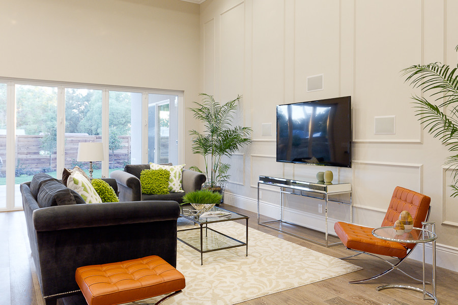 Immagine di un grande soggiorno moderno aperto con pavimento in legno massello medio, TV a parete, pareti beige, nessun camino e pavimento marrone