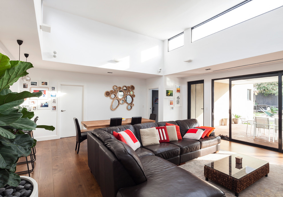 Offenes Modernes Wohnzimmer mit weißer Wandfarbe und braunem Holzboden in Melbourne