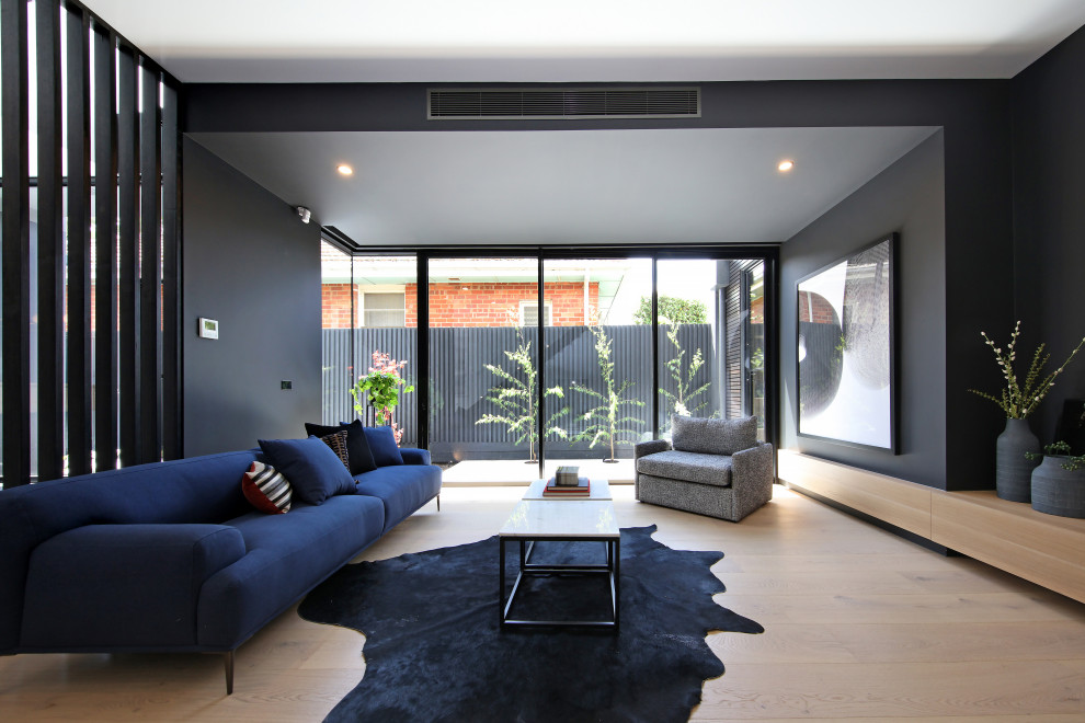Immagine di un soggiorno minimal aperto con pareti nere, parquet chiaro e pavimento beige