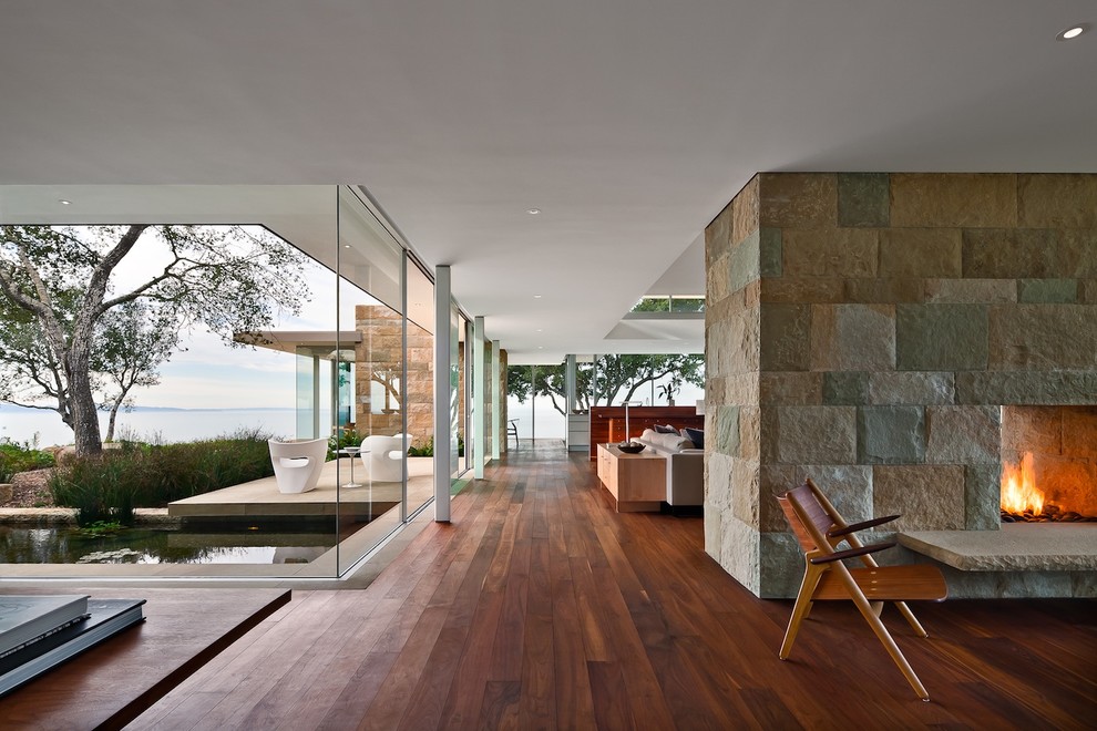 Immagine di un soggiorno minimalista aperto con camino bifacciale