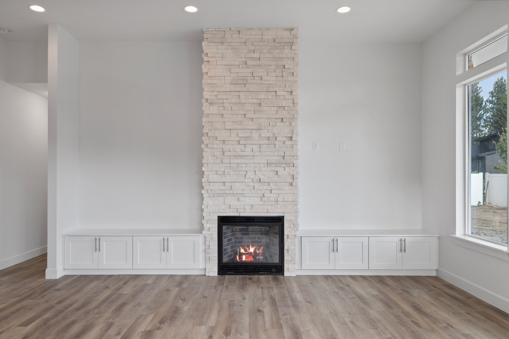 高級な中くらいなコンテンポラリースタイルのおしゃれなLDK (白い壁、ラミネートの床、標準型暖炉、積石の暖炉まわり、壁掛け型テレビ、白い床) の写真