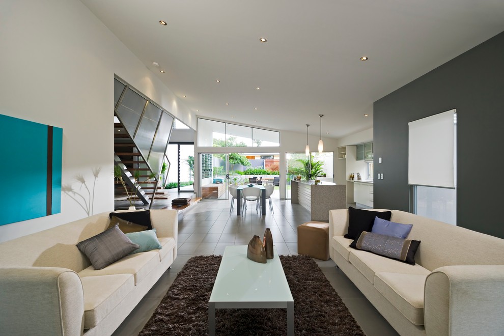Immagine di un grande soggiorno design aperto con pareti bianche, pavimento in gres porcellanato e TV a parete