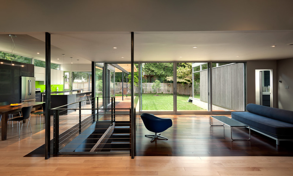 Réalisation d'un salon minimaliste ouvert avec un sol en bois brun et un escalier.