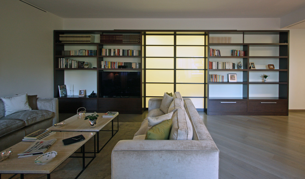 Ejemplo de salón para visitas cerrado moderno grande con paredes beige, suelo de madera en tonos medios y televisor retractable