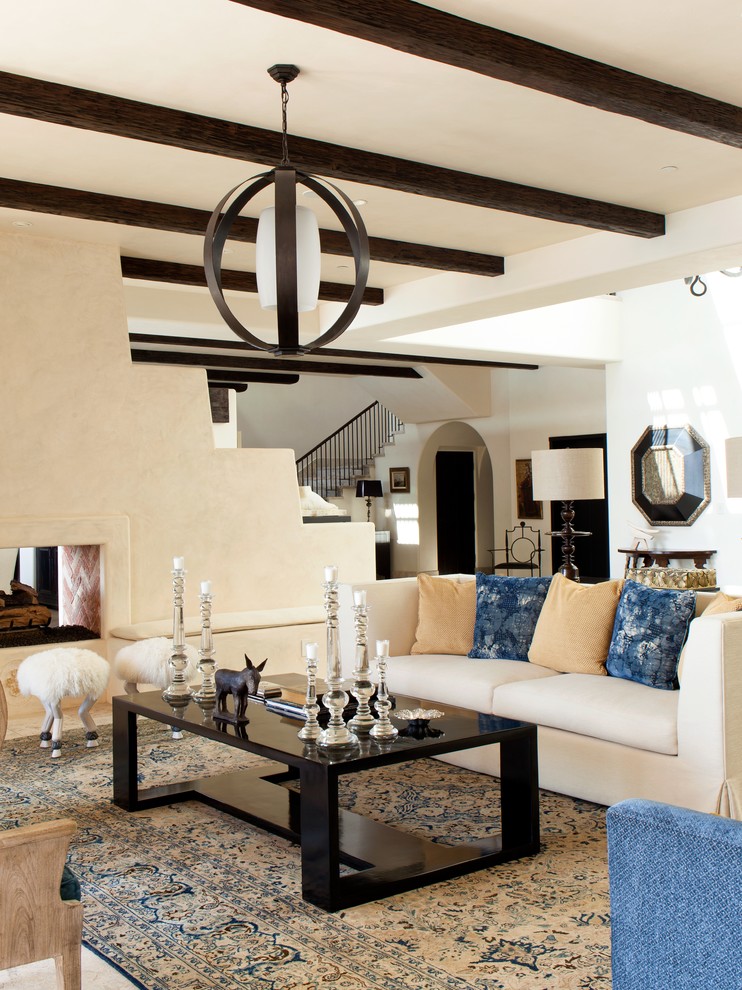 Photo of a medium sized mediterranean formal enclosed living room in Orange County with beige walls, a two-sided fireplace, a plastered fireplace surround, travertine flooring and feature lighting.