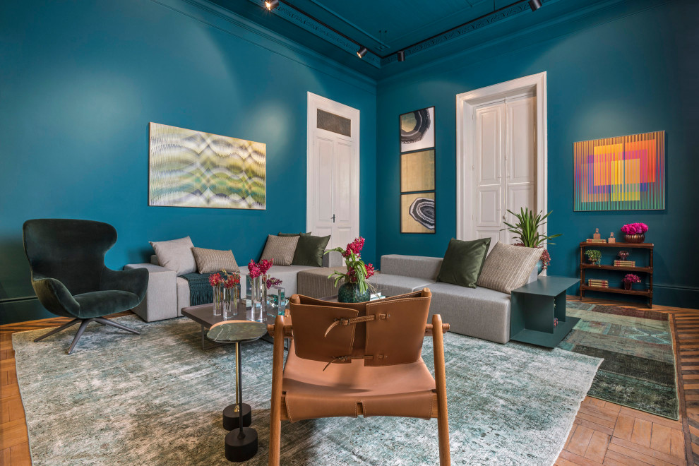 Imagen de salón contemporáneo con paredes azules, suelo de madera en tonos medios y suelo marrón