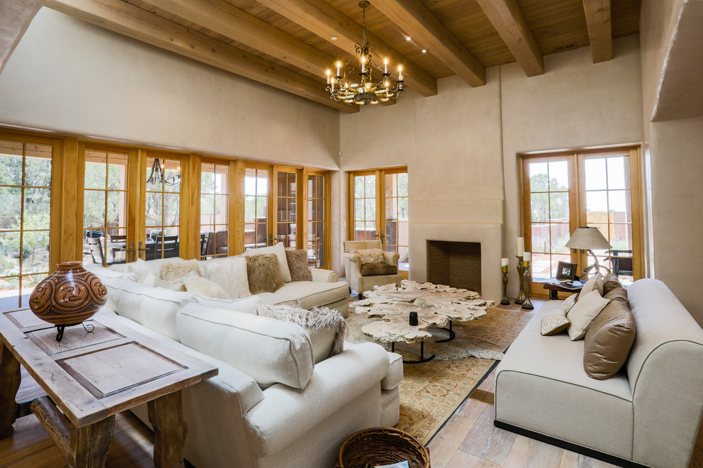 Cette photo montre un salon sud-ouest américain avec un mur beige, un sol en bois brun, une cheminée standard et un sol marron.
