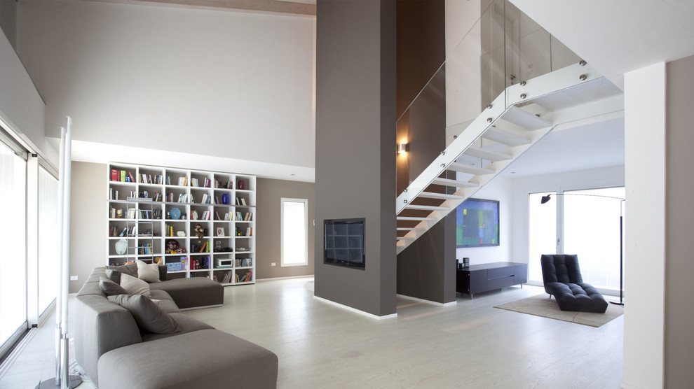 Foto de salón actual extra grande con paredes grises, suelo de madera clara y televisor colgado en la pared