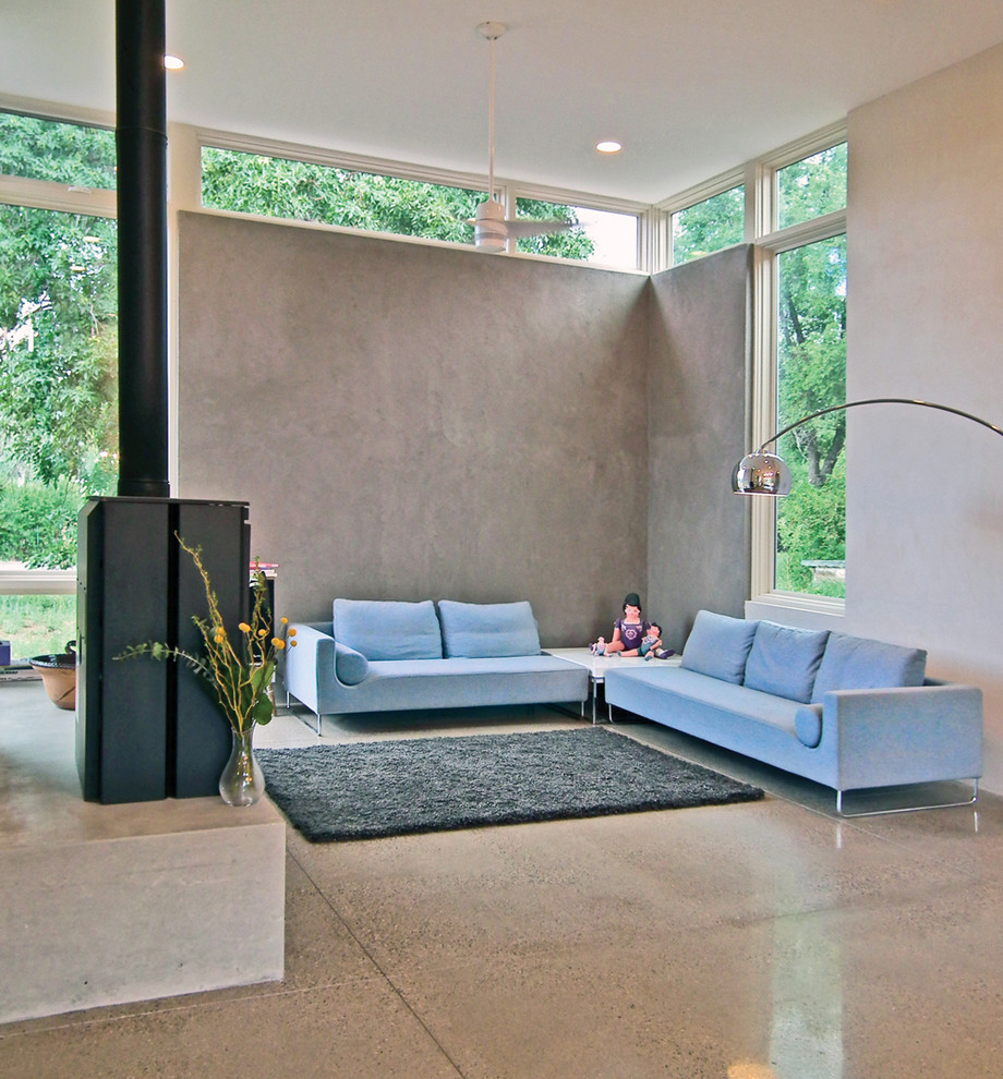 На фото: открытая гостиная комната в современном стиле с серыми стенами, бетонным полом и печью-буржуйкой с