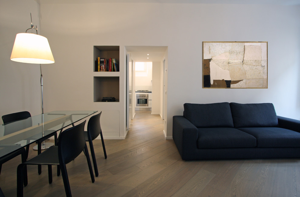 Foto di un piccolo soggiorno minimalista aperto con libreria, pareti bianche, pavimento in legno massello medio e parete attrezzata