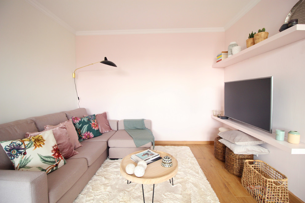 Cette image montre un salon nordique fermé avec une salle de réception, un mur rose, un sol en bois brun, un téléviseur fixé au mur et un sol beige.