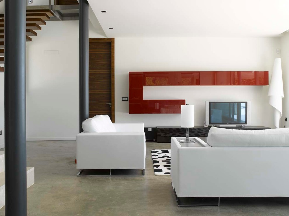 Immagine di un grande soggiorno minimalista con pareti bianche, pavimento in cemento, TV a parete e pavimento grigio