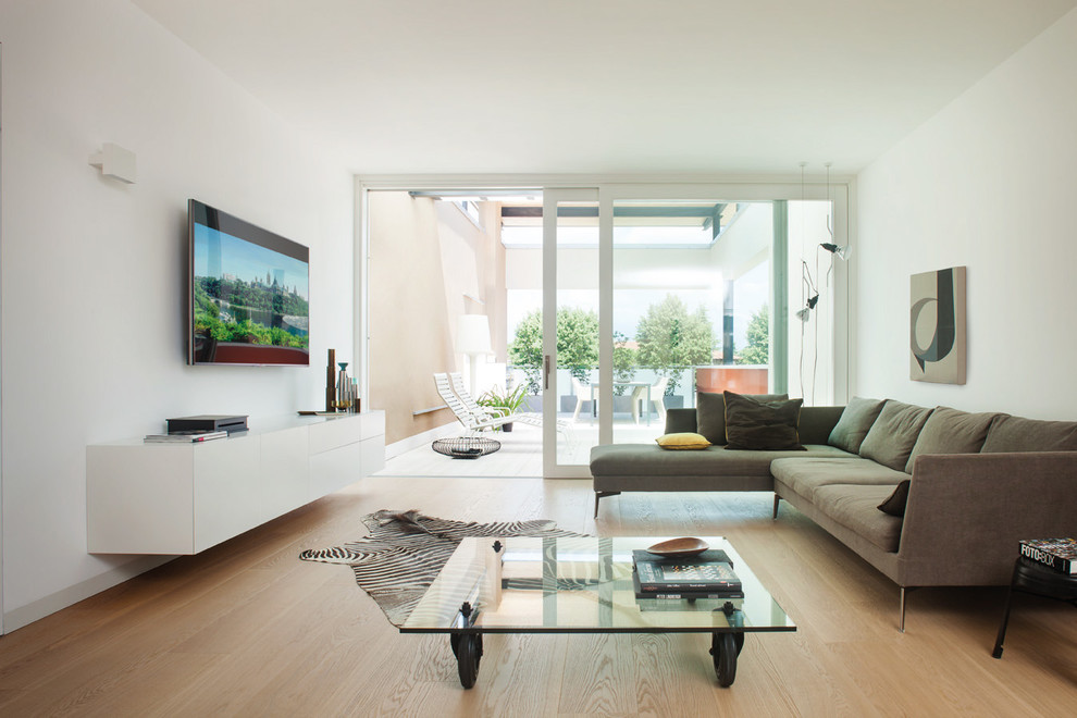На фото: гостиная комната среднего размера в современном стиле с белыми стенами, светлым паркетным полом и телевизором на стене