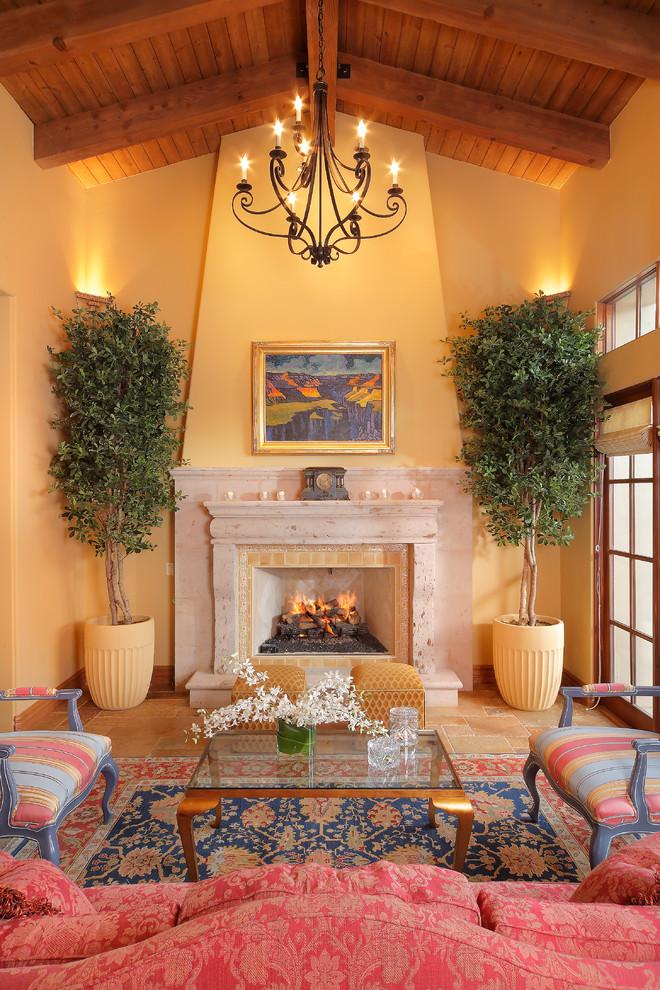 Источник вдохновения для домашнего уюта: гостиная комната в средиземноморском стиле с желтыми стенами, стандартным камином, фасадом камина из камня и ковром на полу