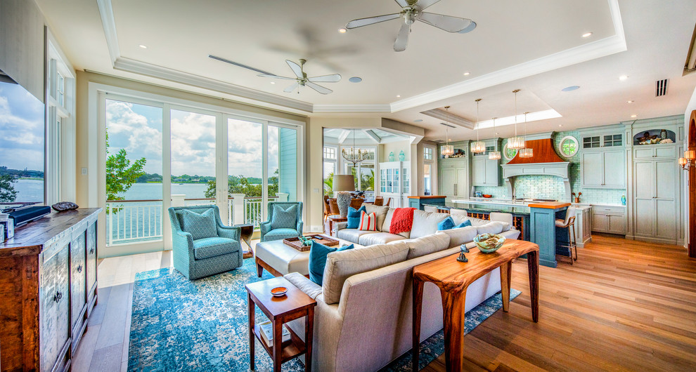 Mittelgroßes, Offenes Maritimes Wohnzimmer mit braunem Boden, beiger Wandfarbe, braunem Holzboden und freistehendem TV in Tampa