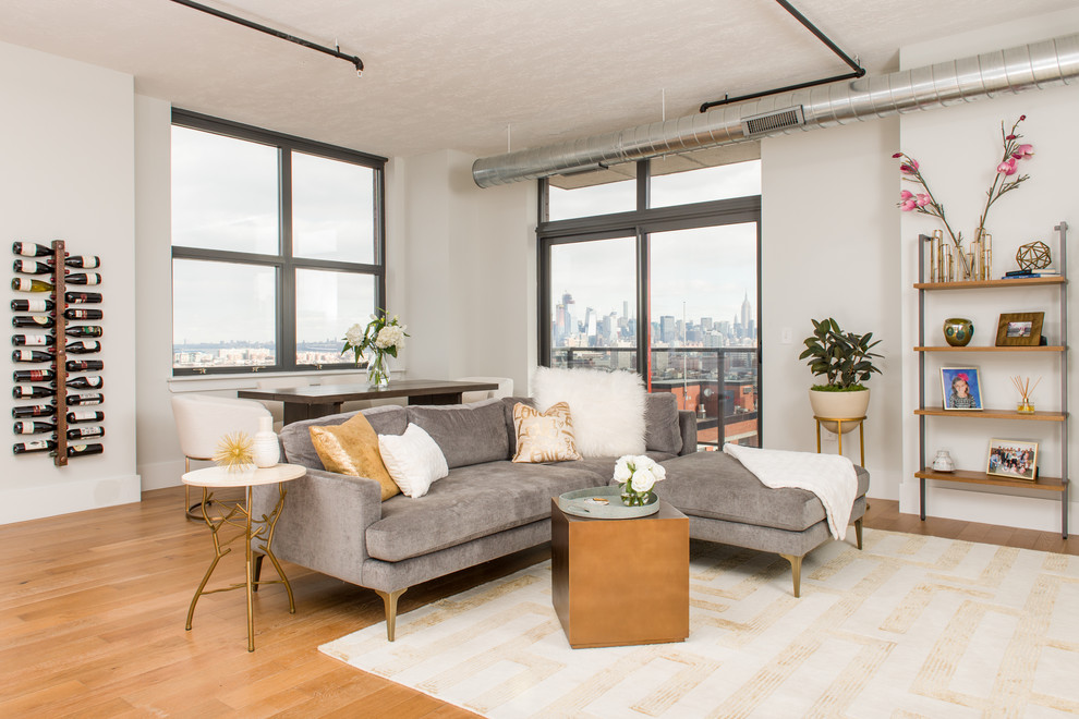 Offenes Modernes Wohnzimmer mit weißer Wandfarbe, hellem Holzboden und beigem Boden in New York