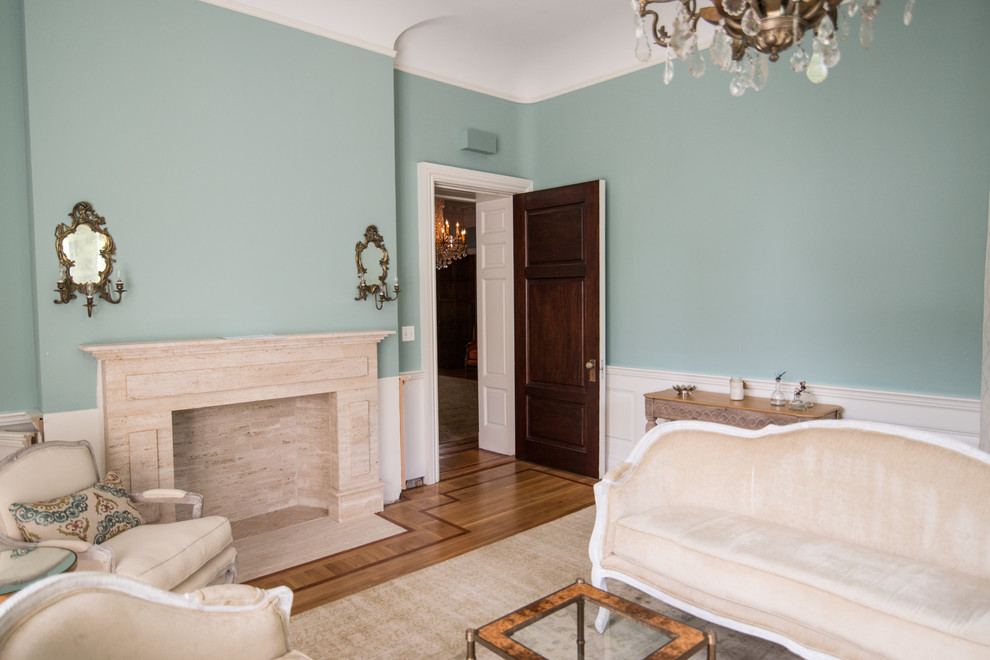 Exempel på ett mellanstort klassiskt separat vardagsrum, med ett finrum, blå väggar, mellanmörkt trägolv, en standard öppen spis, en spiselkrans i sten och brunt golv