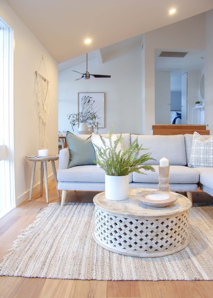 Photo of a beach style formal open plan living room in Sydney with white walls, medium hardwood flooring and beige floors.