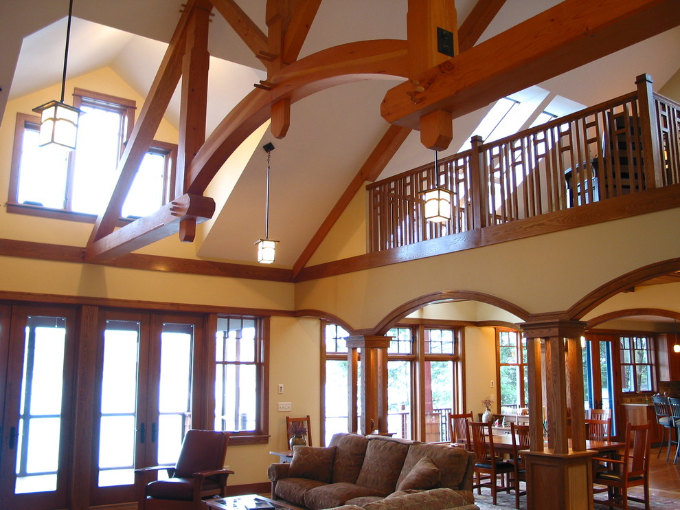 Diseño de salón tipo loft de estilo americano con paredes amarillas, suelo de madera en tonos medios, todas las chimeneas y marco de chimenea de piedra