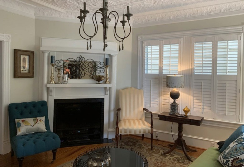 Idée de décoration pour un salon tradition de taille moyenne et fermé avec un mur blanc, un sol en bois brun, une cheminée d'angle et un manteau de cheminée en bois.