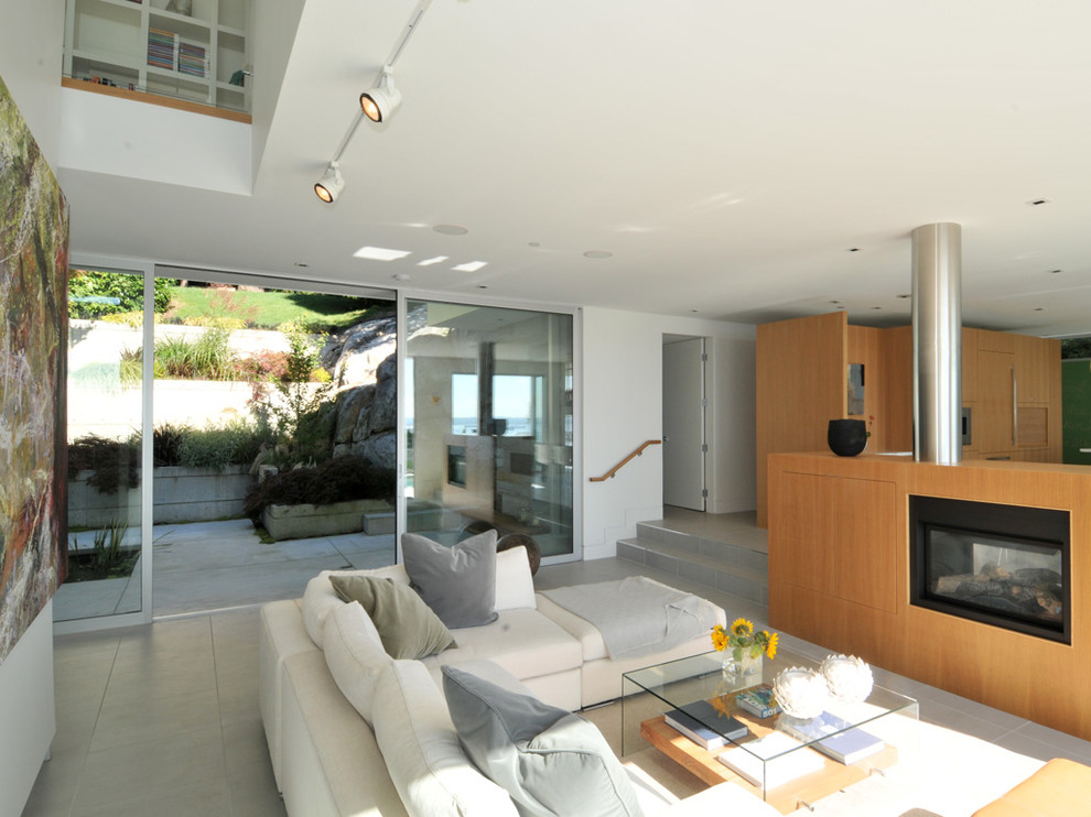 На фото: открытая гостиная комната среднего размера в современном стиле с белыми стенами, полом из керамогранита, стандартным камином, фасадом камина из дерева и скрытым телевизором