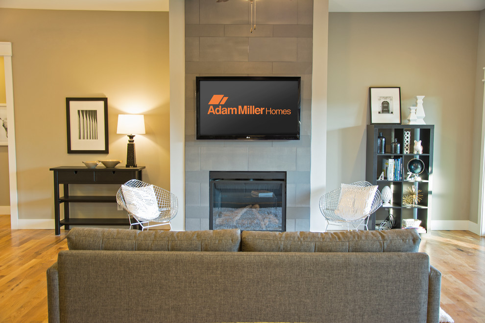Стильный дизайн: открытая гостиная комната в современном стиле с стандартным камином, фасадом камина из плитки и телевизором на стене - последний тренд