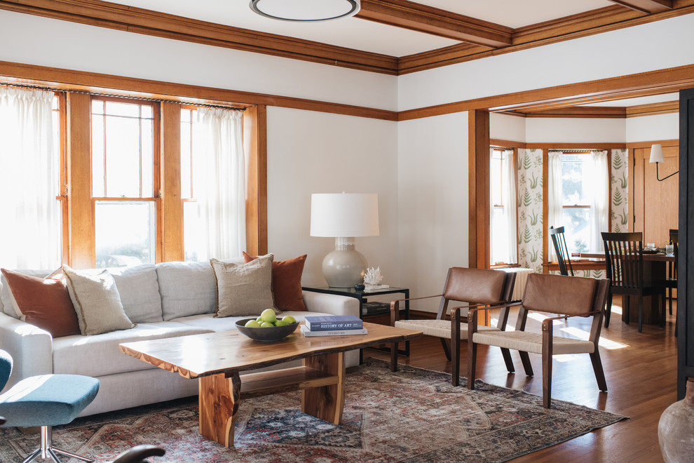 Modelo de salón de estilo americano sin chimenea y televisor con paredes blancas y suelo de madera en tonos medios