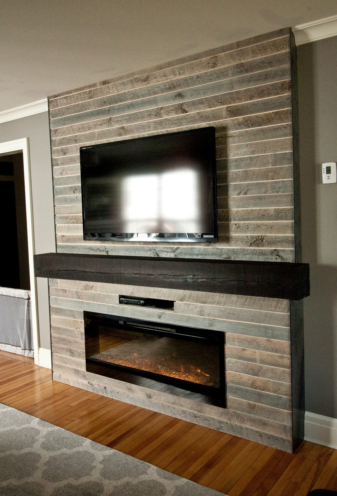 Réalisation d'un petit salon design avec un mur gris, parquet clair, une cheminée standard, un manteau de cheminée en bois, un téléviseur encastré et un sol marron.
