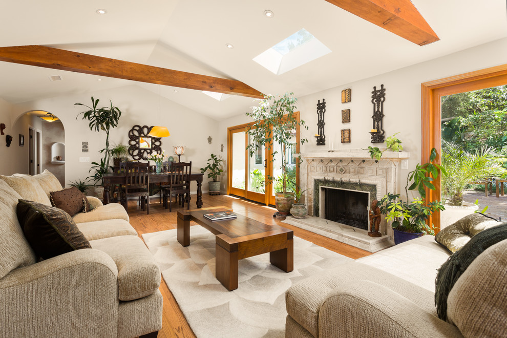This is an example of a medium sized mediterranean formal open plan living room in Los Angeles with white walls, medium hardwood flooring, a standard fireplace, no tv, brown floors and a stone fireplace surround.