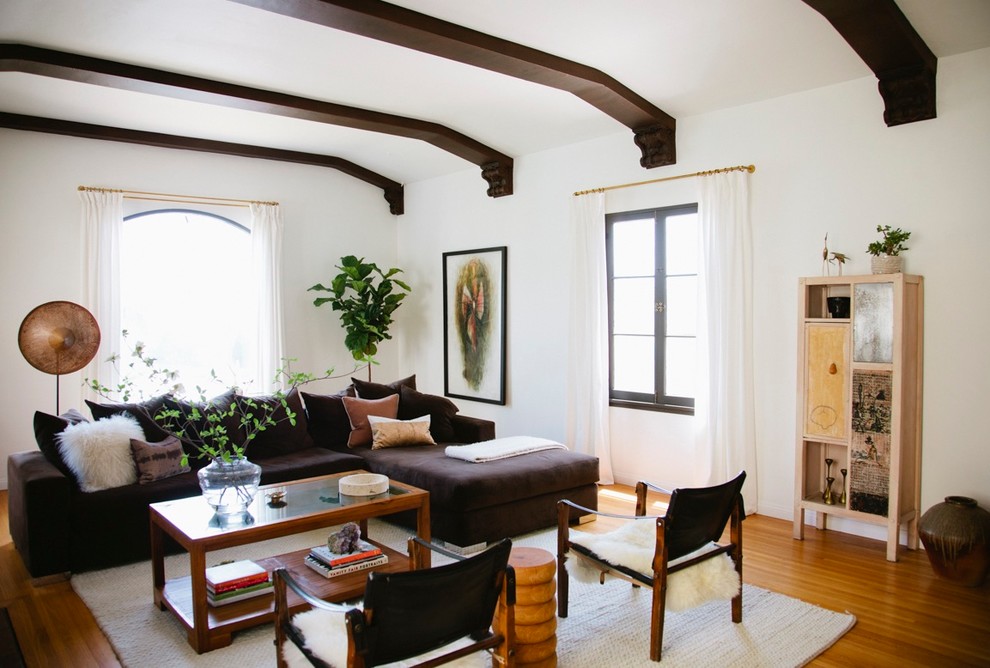 На фото: гостиная комната в стиле фьюжн с белыми стенами, паркетным полом среднего тона и красивыми шторами с