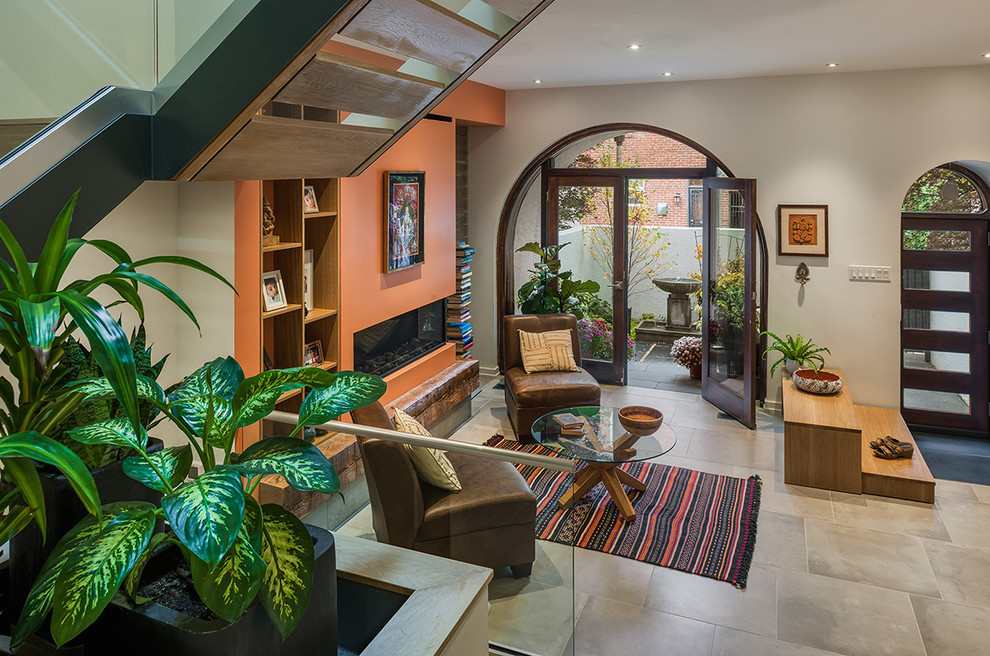 Immagine di un soggiorno design aperto con pareti arancioni, pavimento in gres porcellanato, camino lineare Ribbon e pavimento grigio