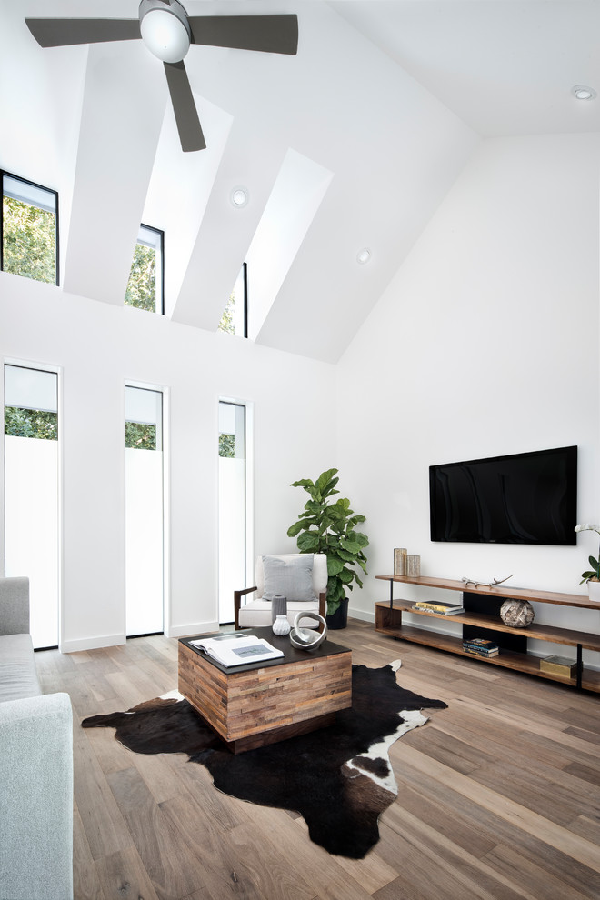 Exempel på ett stort lantligt allrum med öppen planlösning, med ett finrum, vita väggar, mellanmörkt trägolv, en väggmonterad TV och brunt golv