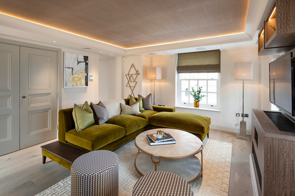 Пример оригинального дизайна: изолированная гостиная комната в современном стиле с белыми стенами, паркетным полом среднего тона, телевизором на стене и бежевым полом